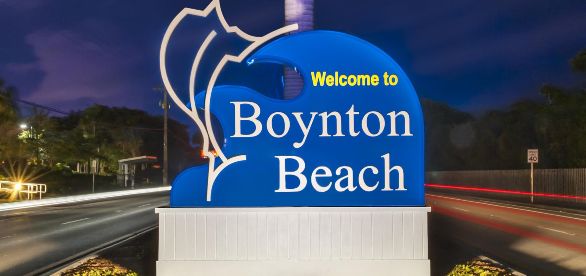 Entry signage for City of Boynton Beach with blue background, white font and silver sailfish