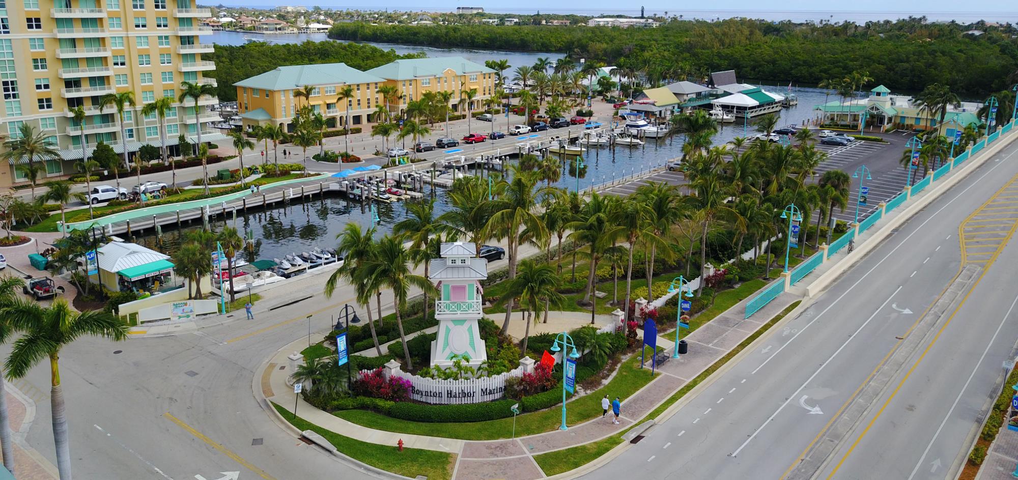 Aerial view of entry signage of Boynton Harbor that is a lighthouse replica surrounded by accent lighting and landscaping